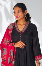 Woman wearing a black dress with red and gold accents against a white background