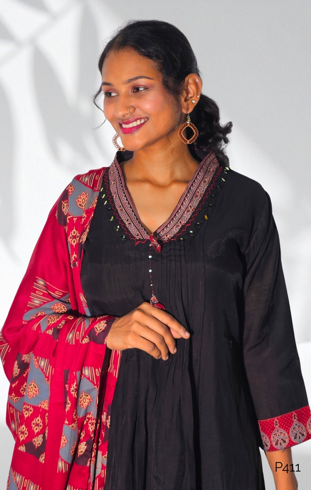 Woman wearing a black dress with red and gold accents against a white background