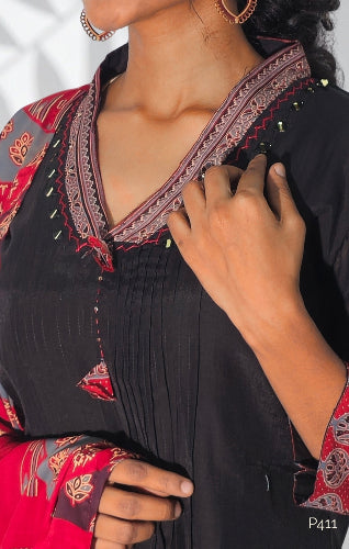 Close-up of a person wearing a black outfit with red and gold embroidery.