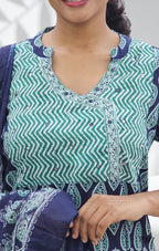 Person wearing a green and blue patterned outfit with a blurred background
