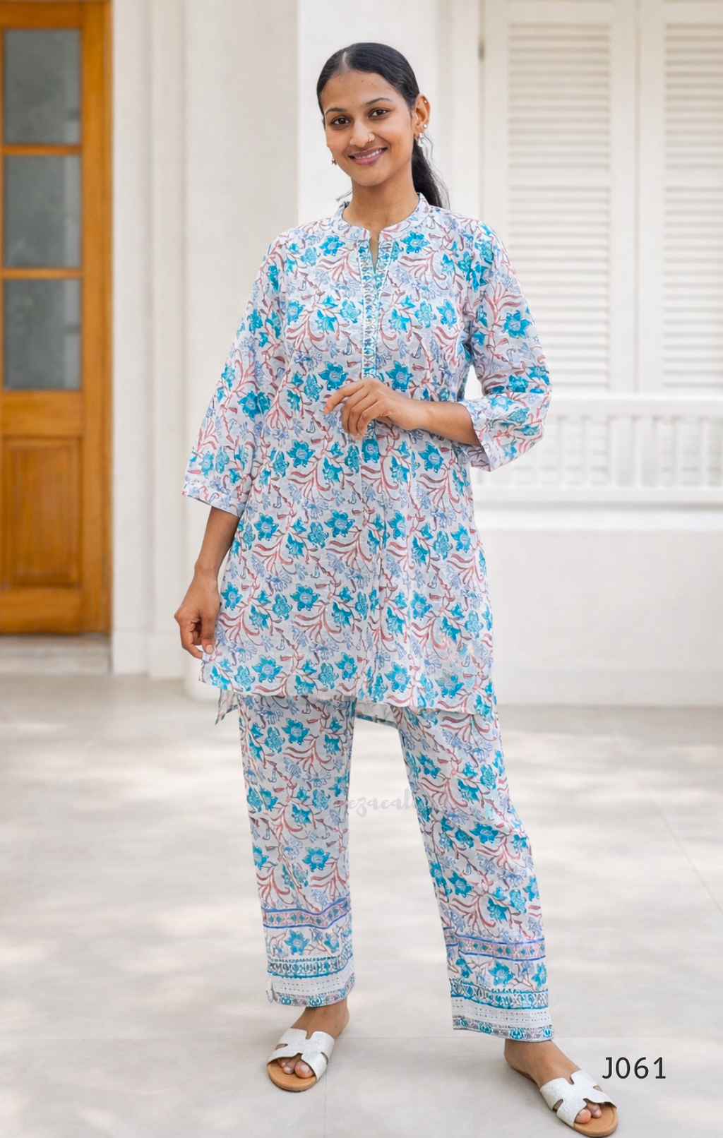 Woman wearing a floral kurta and pants set in a bright room.