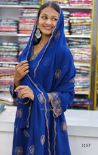 Woman wearing a blue embroidered saree in a fabric store.