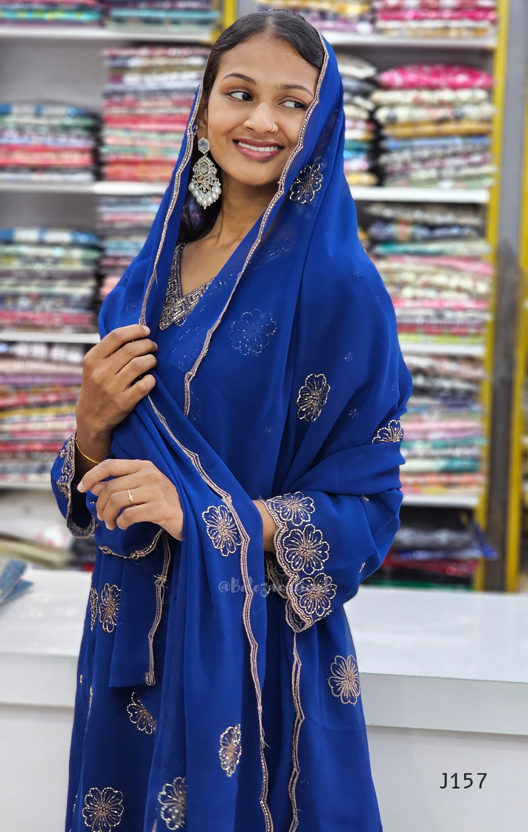 Woman wearing a blue embroidered saree in a fabric store.