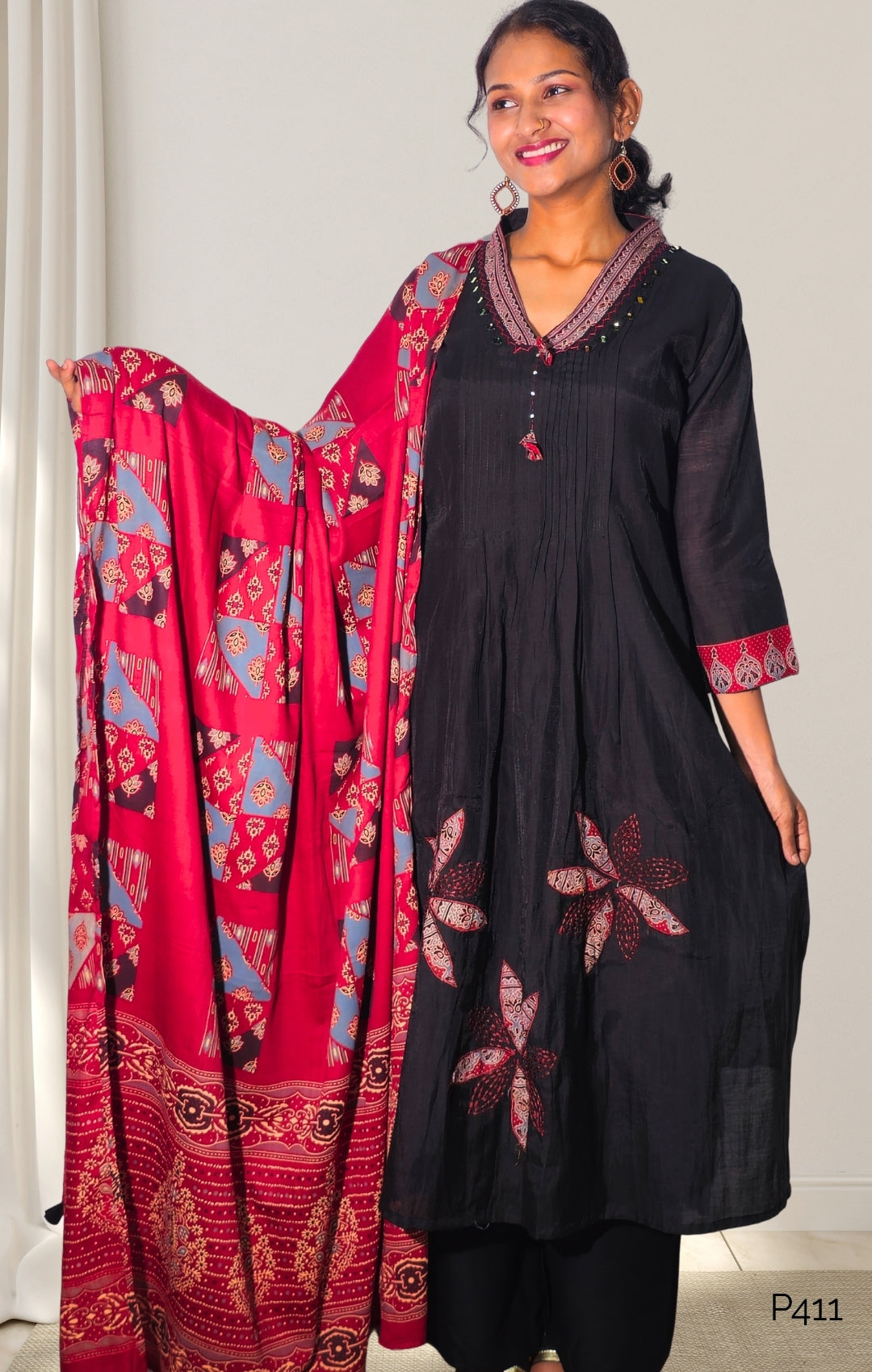 Woman wearing a black outfit with a red patterned dupatta against a white background