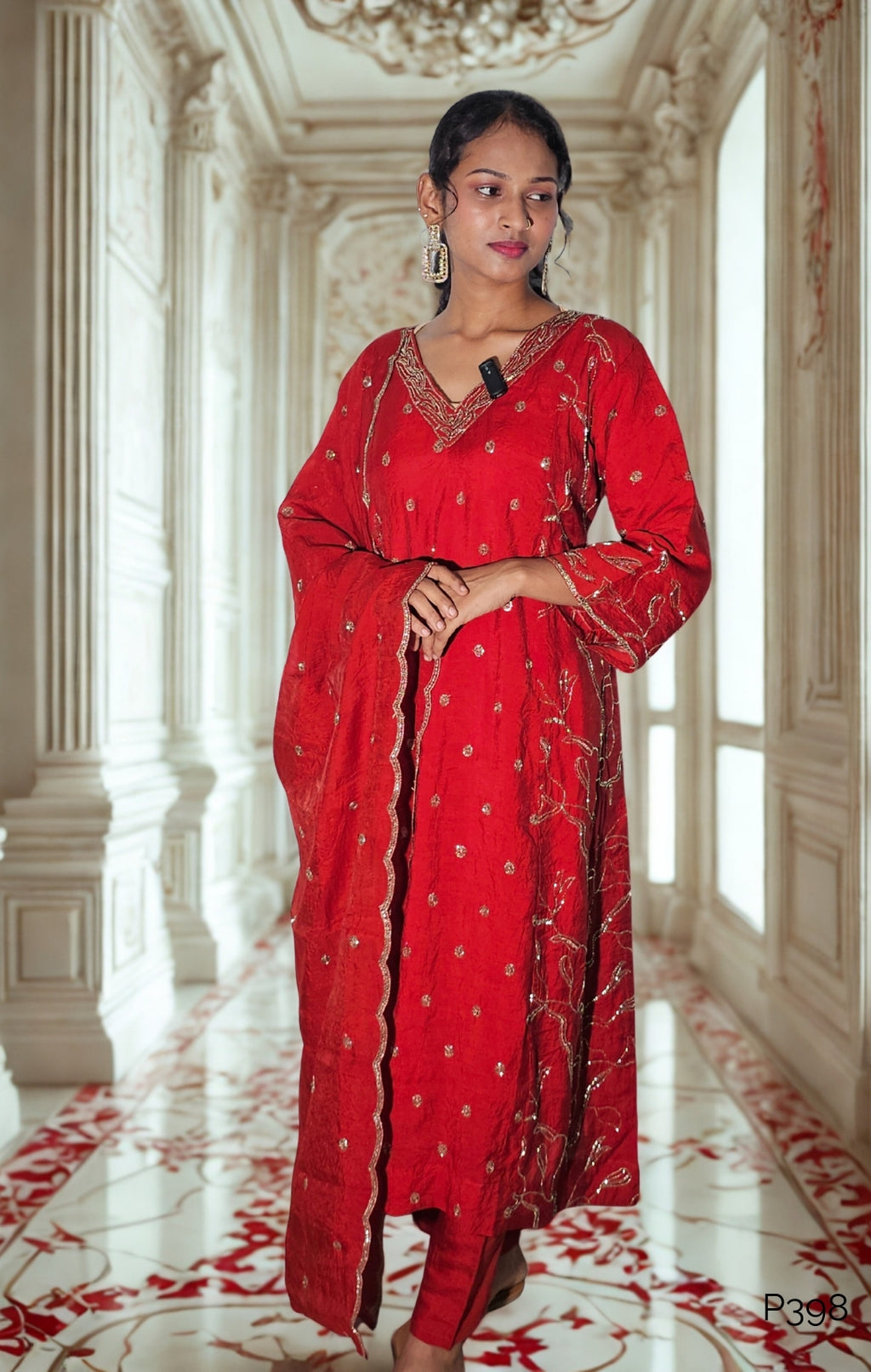 Woman in a red traditional outfit standing in an ornate room with white walls and red accents.