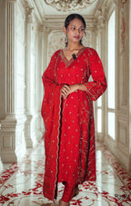 Woman in a red traditional outfit standing in an ornate room with white walls and red accents.