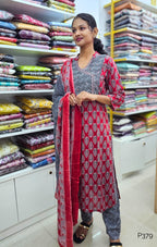 Woman in a patterned outfit standing in a fabric store with shelves of colorful fabrics.