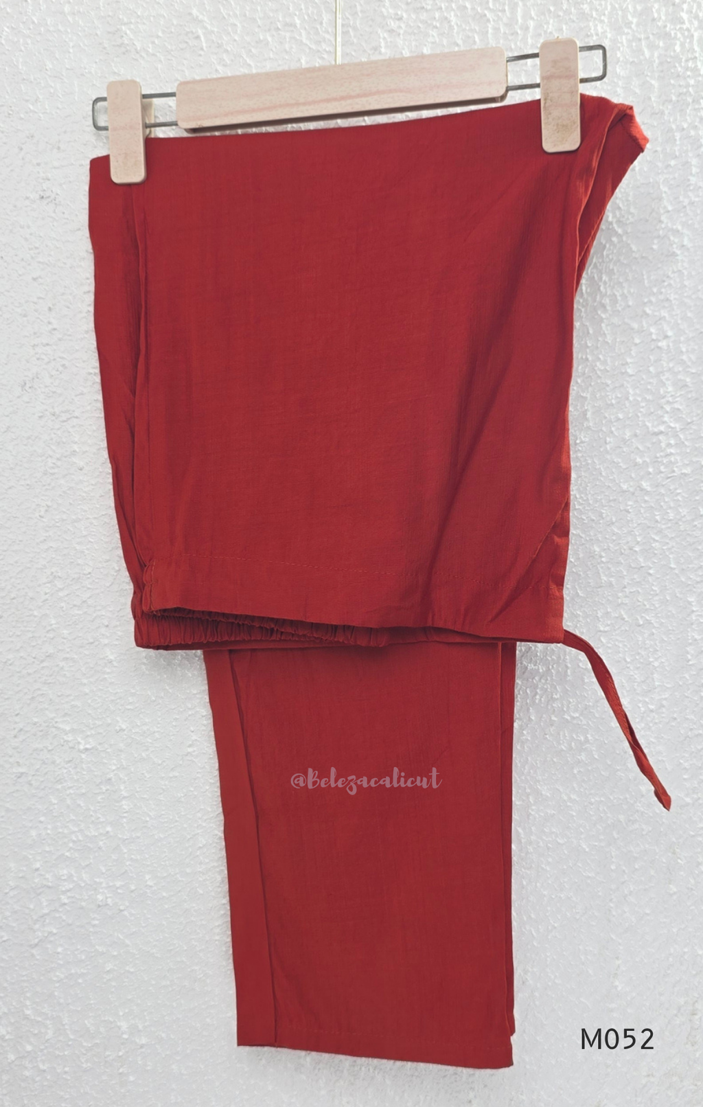 Red sleeveless top and pants set on a hanger against a white background