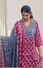 Woman wearing a red and black patterned outfit with a matching shawl indoors.