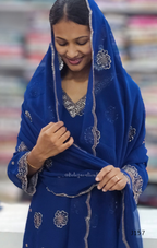 Woman wearing a blue embroidered traditional outfit with a blurred background