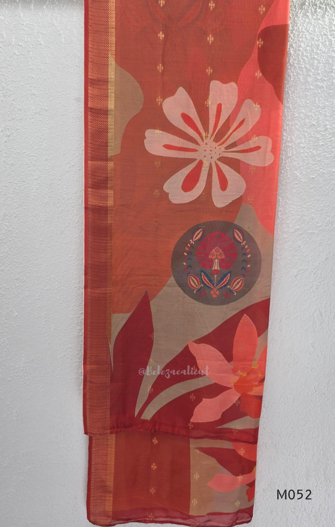 Red fabric with floral patterns and a central emblem on a white background