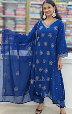 Woman wearing a blue traditional outfit with floral patterns indoors.