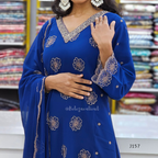 Woman wearing a blue embroidered dress in a fabric store.