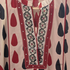 Beige cotton churidar set with red and black teardrop print, embroidered neckline, contrast red bottom and printed dupatta.