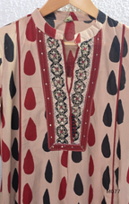 Beige cotton churidar set with red and black teardrop print, embroidered neckline, contrast red bottom and printed dupatta.