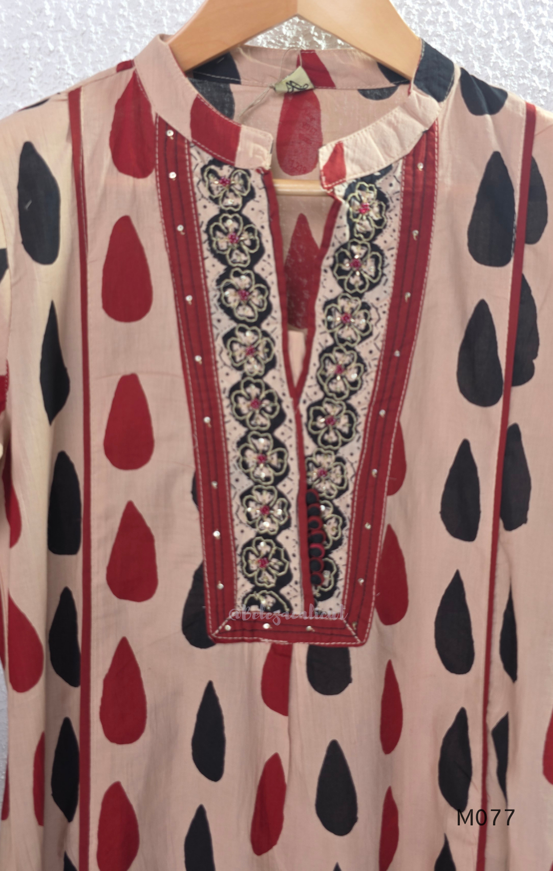 Beige cotton churidar set with red and black teardrop print, embroidered neckline, contrast red bottom and printed dupatta.