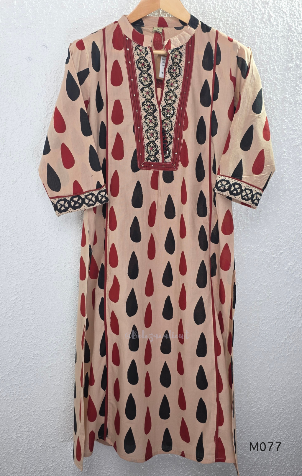 Beige cotton churidar set with red and black teardrop print, embroidered neckline, contrast red bottom and printed dupatta.
