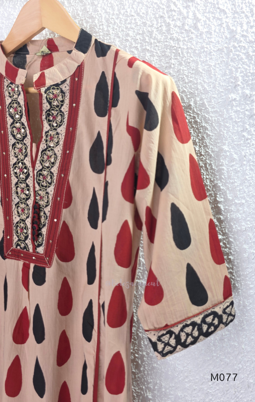 Beige cotton churidar set with red and black teardrop print, embroidered neckline, contrast red bottom and printed dupatta.
