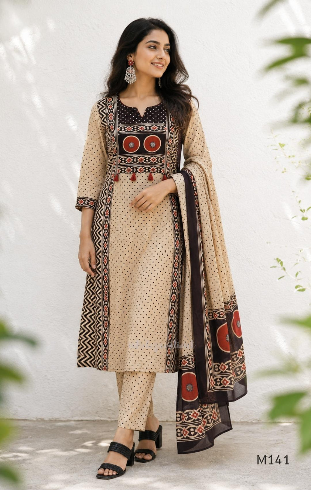 Beige cotton churidar set with dark brown geometric print, red accents, mirror-work yoke, tassels and coordinated dupatta.