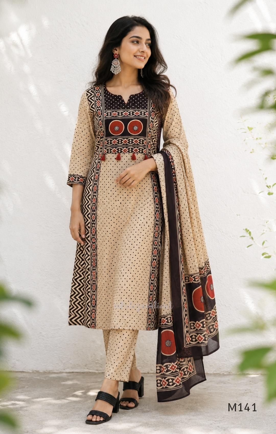 Beige cotton churidar set with dark brown geometric print, red accents, mirror-work yoke, tassels and coordinated dupatta.