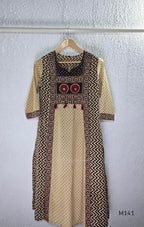Beige cotton churidar set with dark brown geometric print, red accents, mirror-work yoke, tassels and coordinated dupatta.