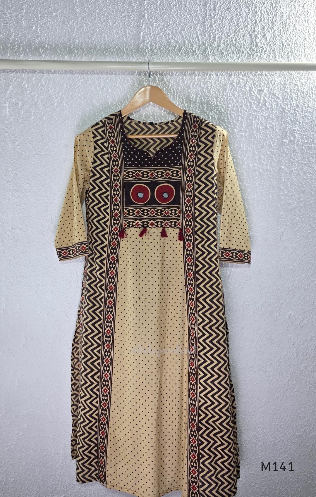 Beige cotton churidar set with dark brown geometric print, red accents, mirror-work yoke, tassels and coordinated dupatta.