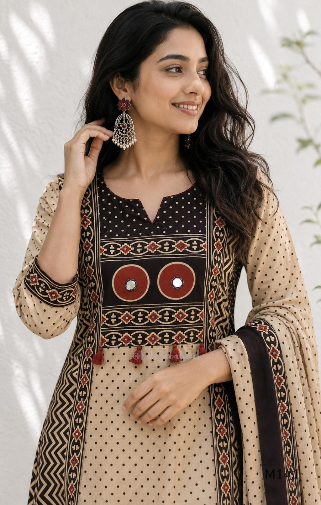 Beige cotton churidar set with dark brown geometric print, red accents, mirror-work yoke, tassels and coordinated dupatta.