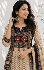 Beige cotton churidar set with dark brown geometric print, red accents, mirror-work yoke, tassels and coordinated dupatta.