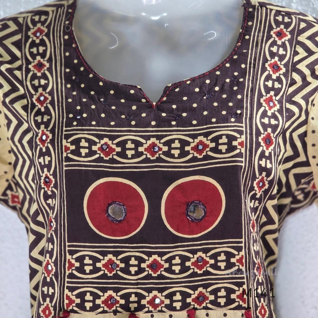 Beige cotton churidar set with dark brown geometric print, red accents, mirror-work yoke, tassels and coordinated dupatta.