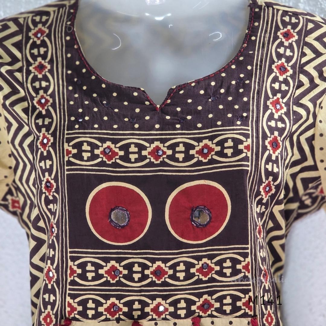 Beige cotton churidar set with dark brown geometric print, red accents, mirror-work yoke, tassels and coordinated dupatta.