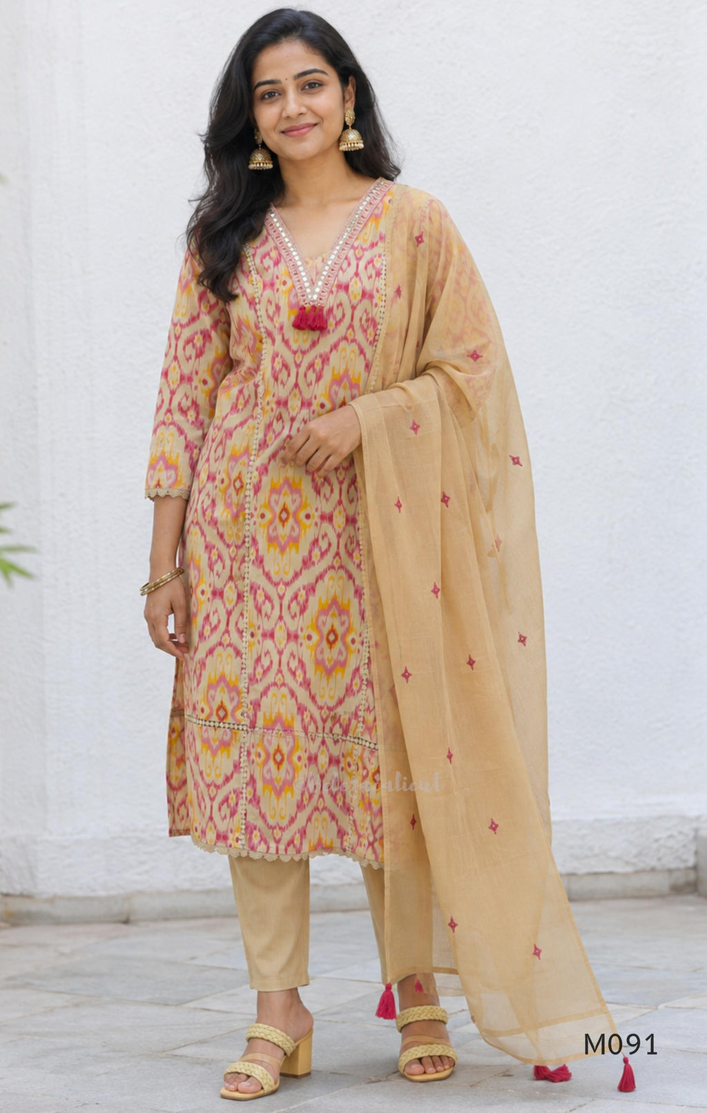 Warm beige cotton 3-piece churidar set with pink and mustard ikat-style print, mirror-trimmed V-neck, plain beige bottom and matching dupatta.