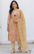 Warm beige cotton 3-piece churidar set with pink and mustard ikat-style print, mirror-trimmed V-neck, plain beige bottom and matching dupatta.