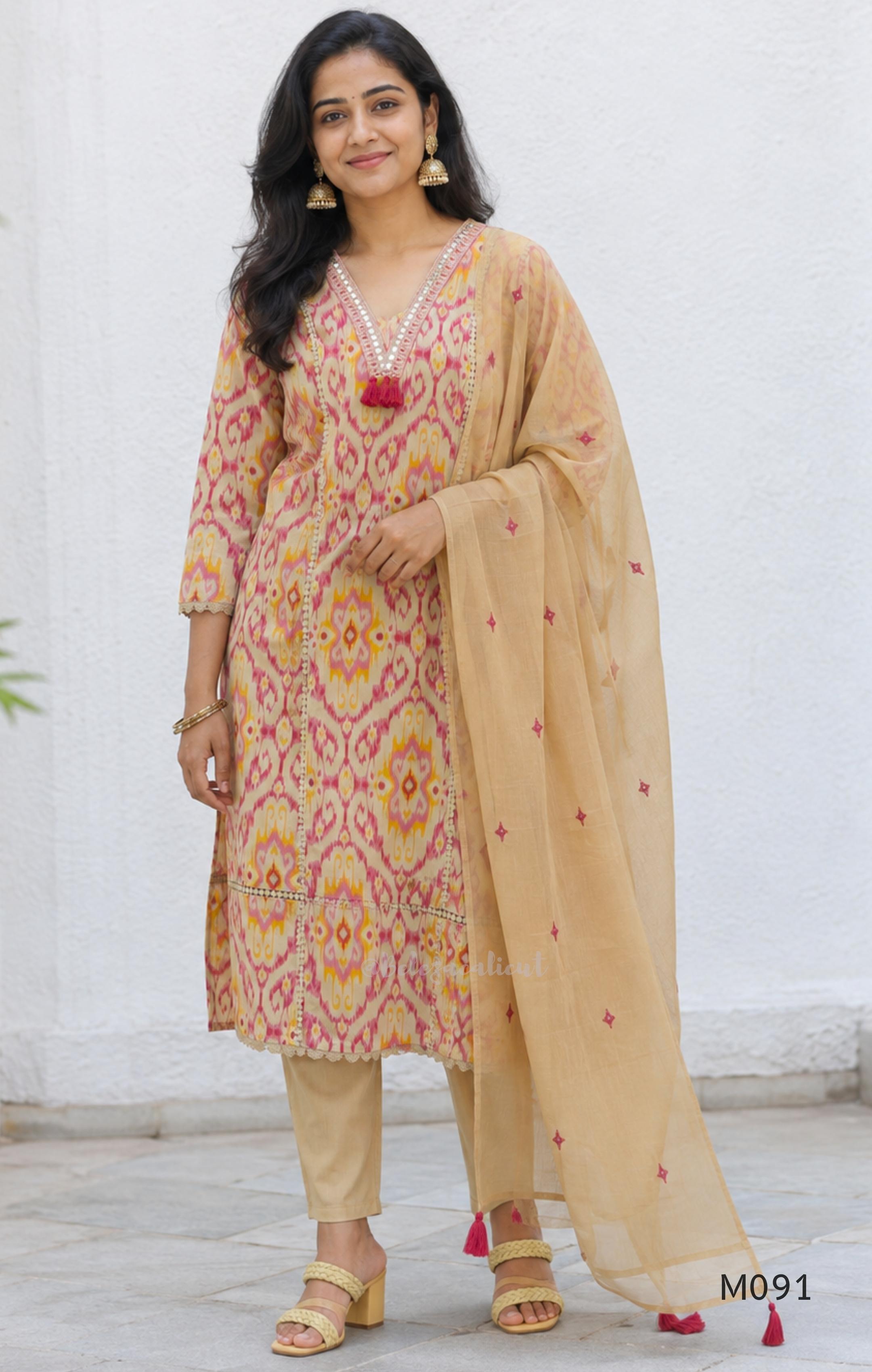 Warm beige cotton 3-piece churidar set with pink and mustard ikat-style print, mirror-trimmed V-neck, plain beige bottom and matching dupatta.