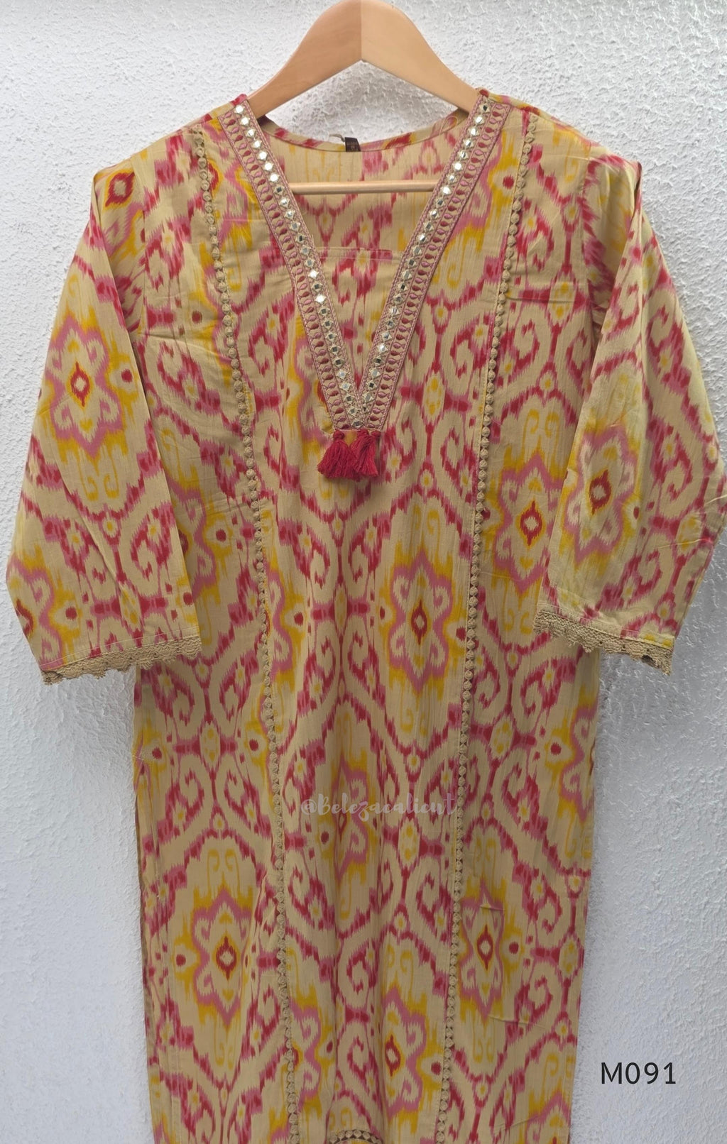 Warm beige cotton 3-piece churidar set with pink and mustard ikat-style print, mirror-trimmed V-neck, plain beige bottom and matching dupatta.