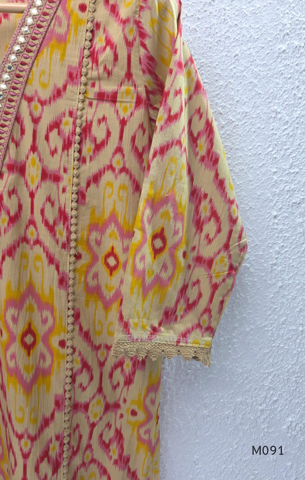 Warm beige cotton 3-piece churidar set with pink and mustard ikat-style print, mirror-trimmed V-neck, plain beige bottom and matching dupatta.