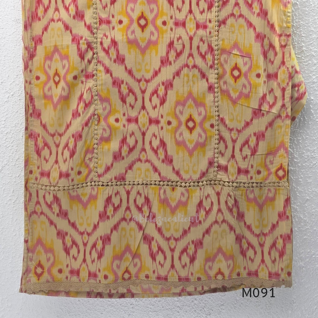 Warm beige cotton 3-piece churidar set with pink and mustard ikat-style print, mirror-trimmed V-neck, plain beige bottom and matching dupatta.