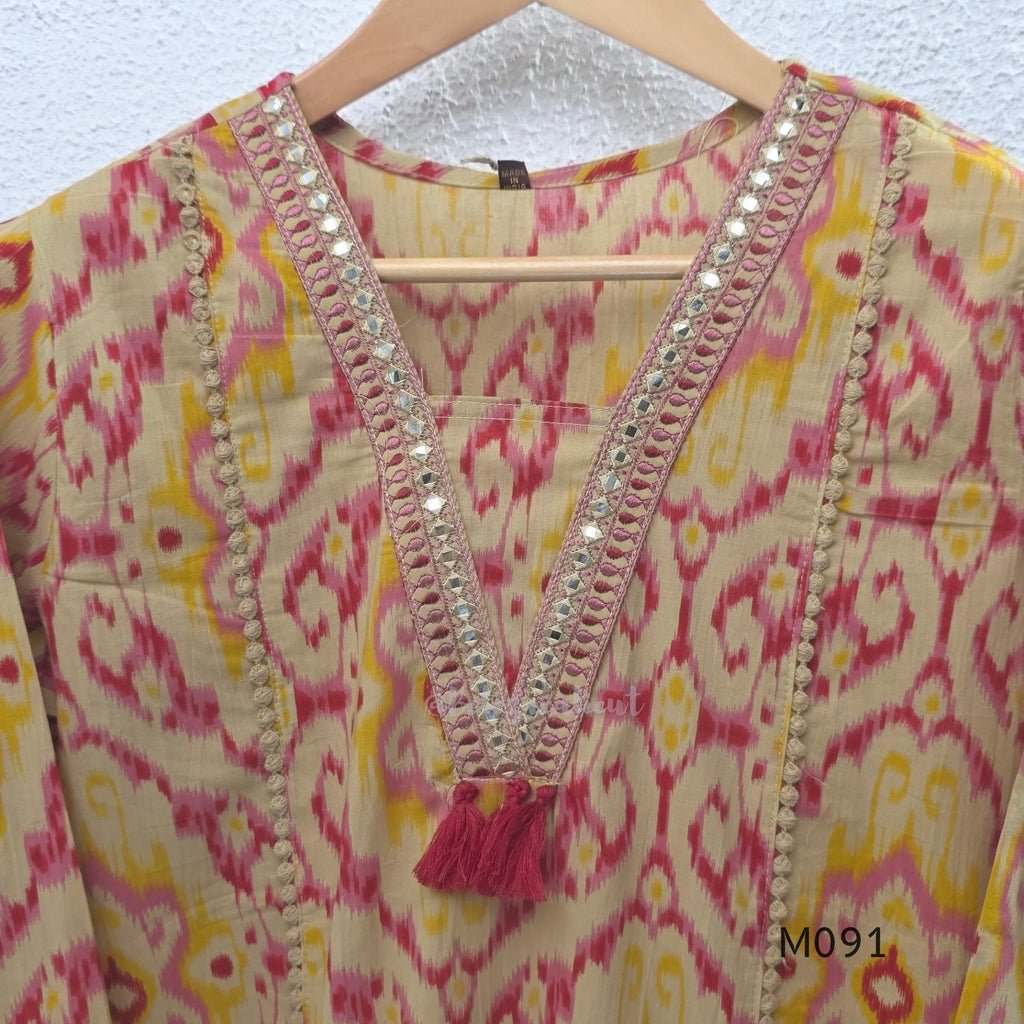 Warm beige cotton 3-piece churidar set with pink and mustard ikat-style print, mirror-trimmed V-neck, plain beige bottom and matching dupatta.