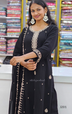 Woman wearing a black embroidered outfit with a colorful fabric background