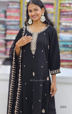 Woman wearing a black outfit with intricate silver embroidery in a store setting.