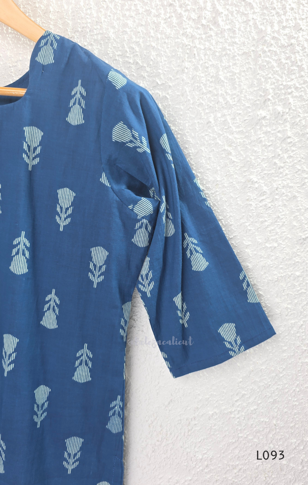 Blue cotton women’s top with light leaf print, notch neckline, elbow-length sleeves, and straight everyday fit.