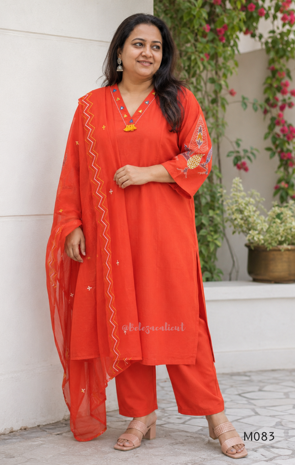 Bright orange cotton plus size churidar set with tassel V-neck, embroidered sleeve detail, matching bottom and dupatta.