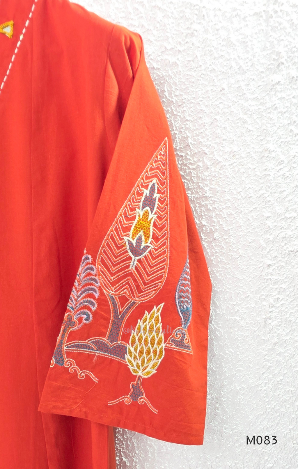 Bright orange cotton plus size churidar set with tassel V-neck, embroidered sleeve detail, matching bottom and dupatta.