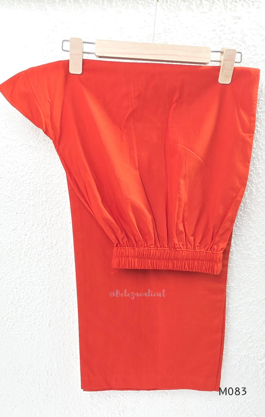 Bright orange cotton plus size churidar set with tassel V-neck, embroidered sleeve detail, matching bottom and dupatta.