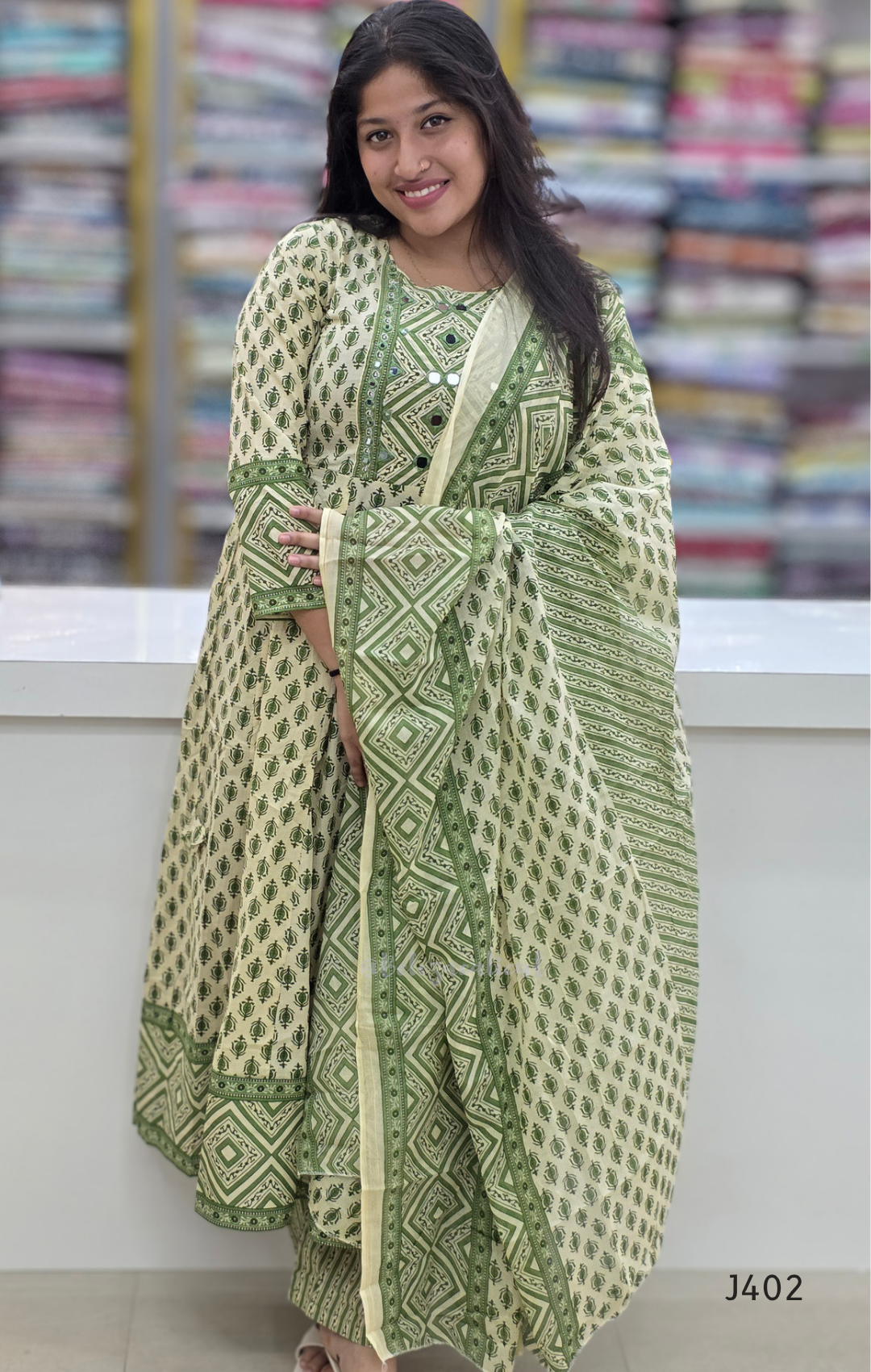 Woman wearing a green and white patterned outfit in a fabric store.