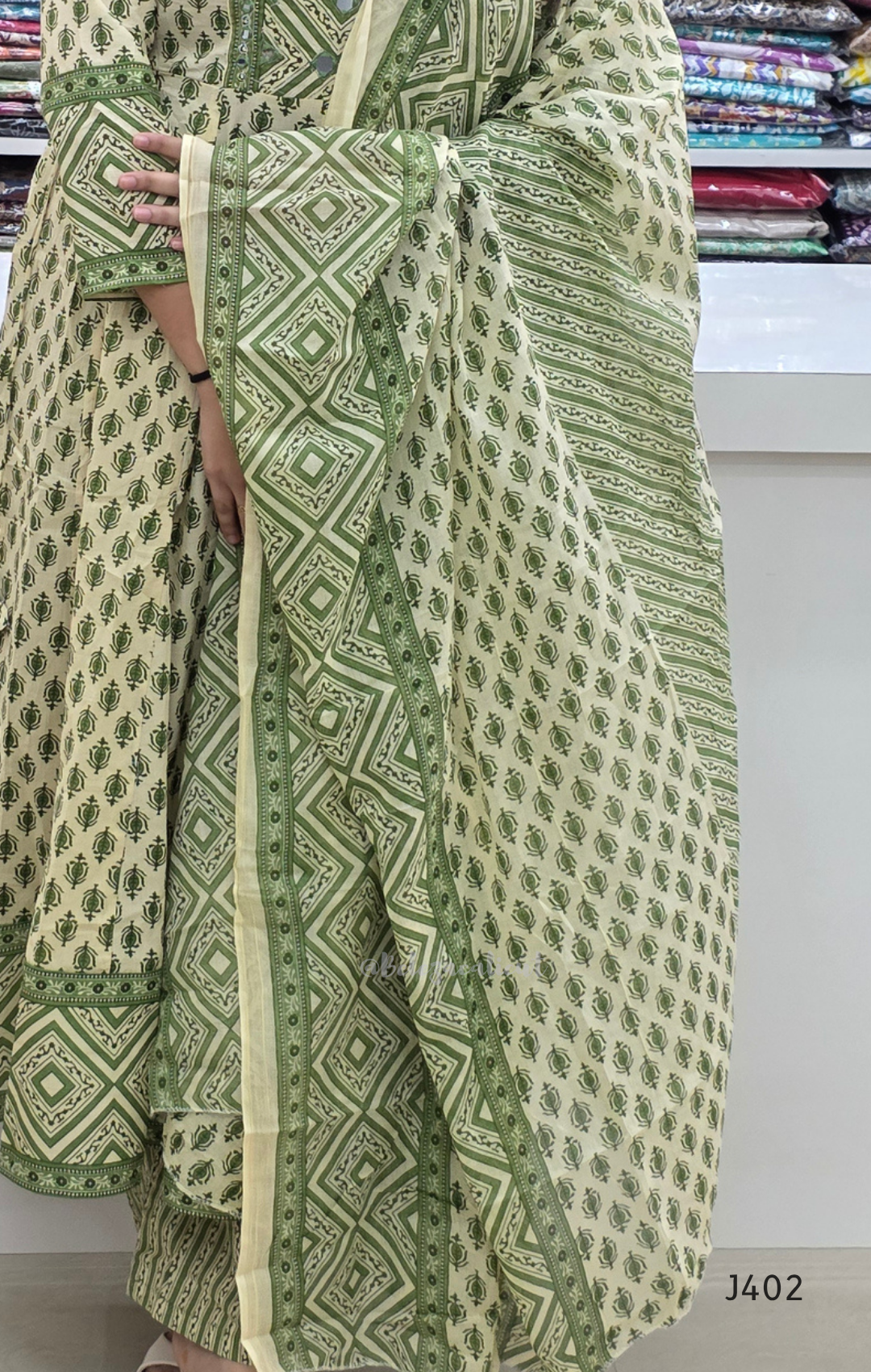 Green and white patterned fabric with a visible brand label on a plain background