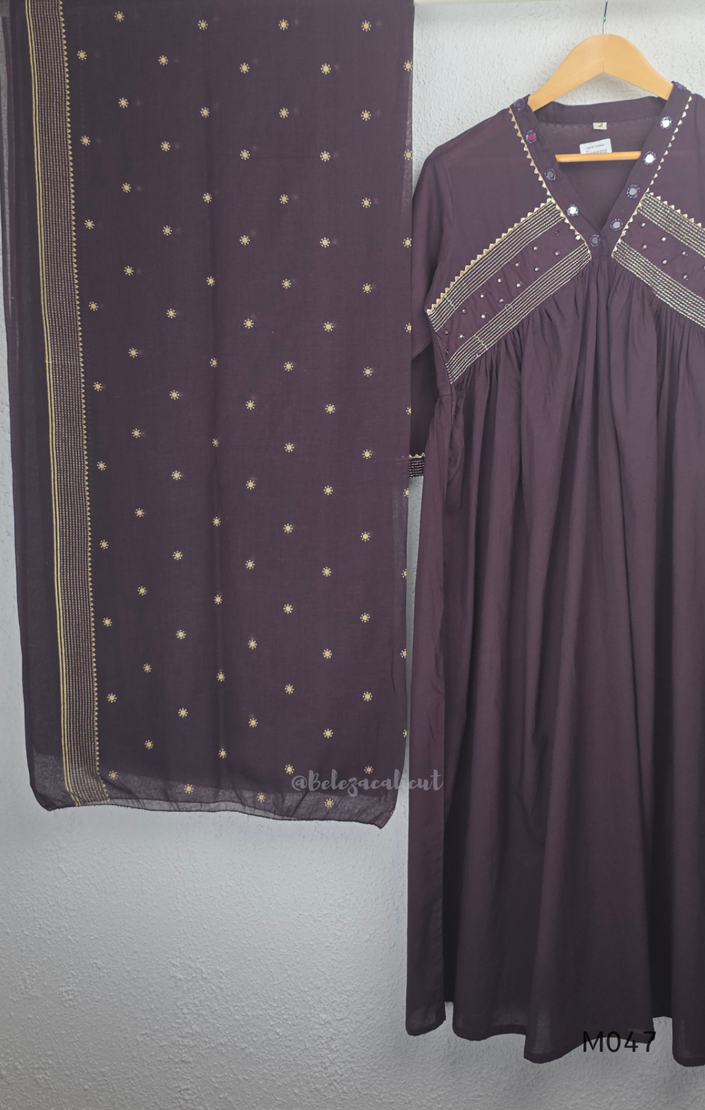 Deep plum cotton churidar suit set with matching bottom and dupatta, mirror detail V-neckline, gold line work on yoke, and elegant festive casual styling.