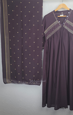 Deep plum cotton churidar suit set with matching bottom and dupatta, mirror detail V-neckline, gold line work on yoke, and elegant festive casual styling.