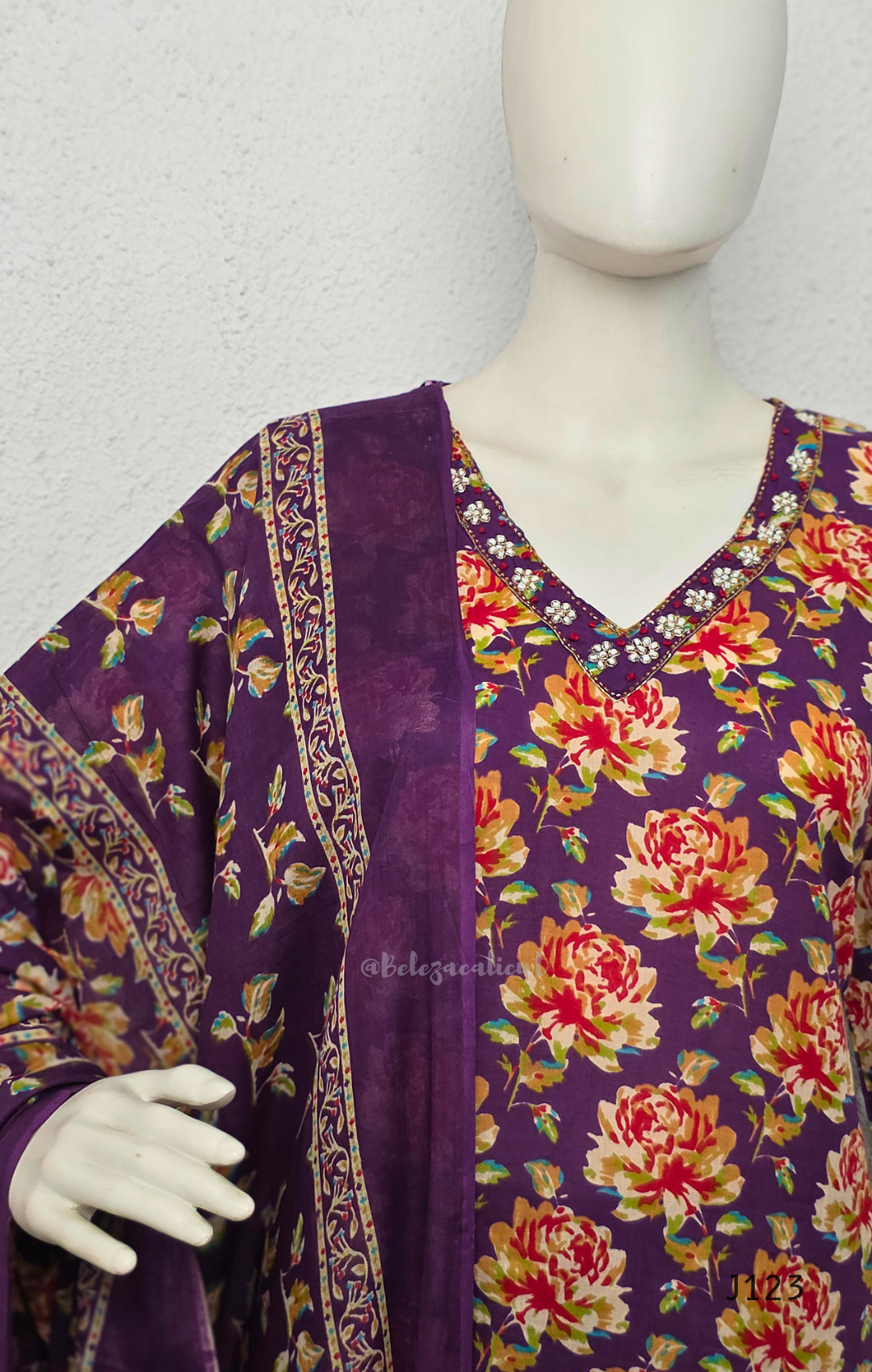 Deep purple cotton churidar set with rose floral print, matching dupatta, 3/4 sleeves, and embellished V-neckline displayed on mannequin.