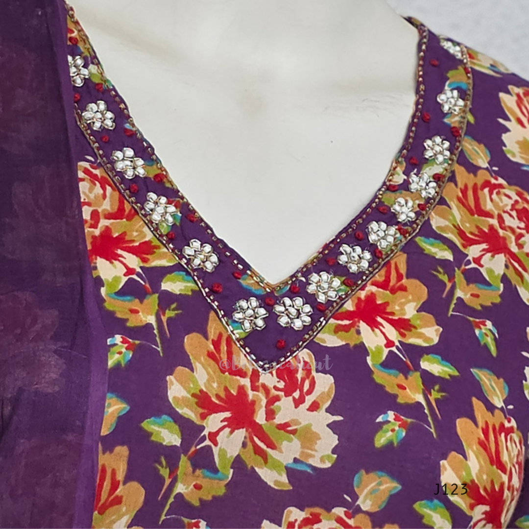 Deep purple cotton churidar set with rose floral print, matching dupatta, 3/4 sleeves, and embellished V-neckline displayed on mannequin.