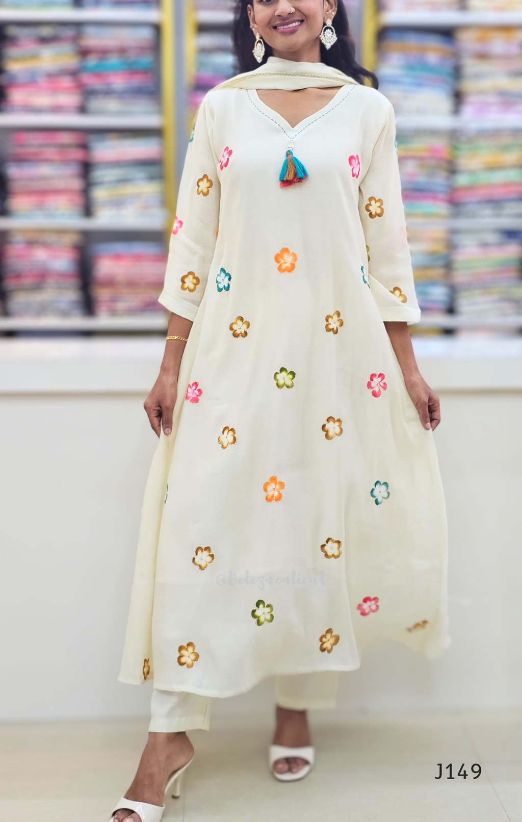 Woman wearing a cream-colored outfit with floral embroidery in a store setting